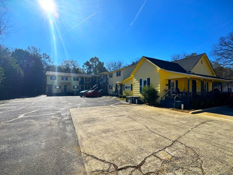 A yellow building with a parking lot in front of it.
