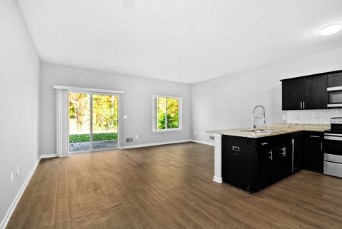 A kitchen with black cabinets and a wooden floor.