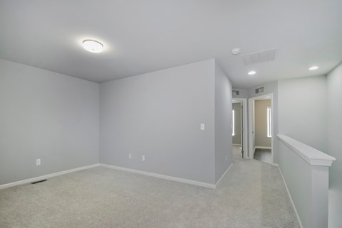 A spacious empty room with a carpeted floor and white walls.