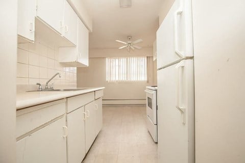 A white kitchen with a sink, stove, and refrigerator.