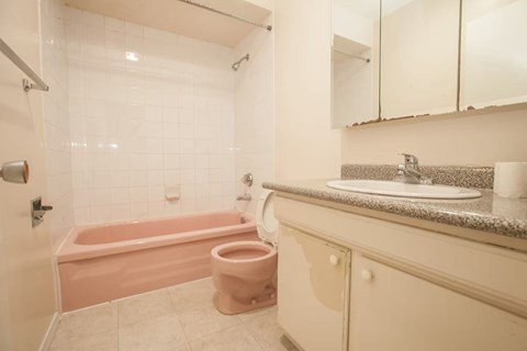A bathroom with a pink tub and toilet.