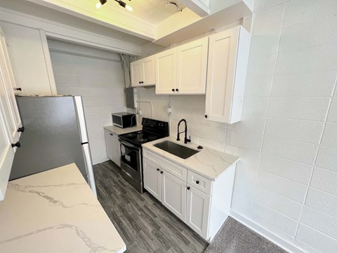 A kitchen with white cabinets and a black refrigerator.