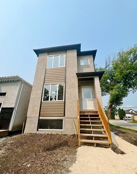 A modern house with a wooden staircase leading to the entrance.