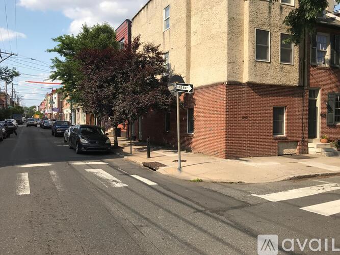 A street view with cars parked on the side and a building with a sign that reads "AVAIL".