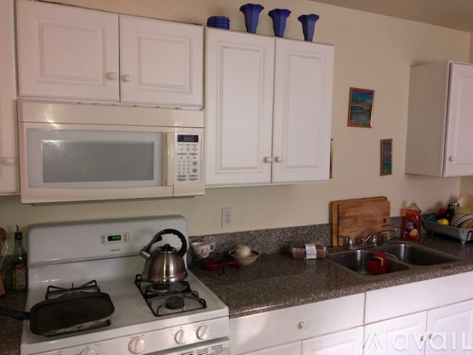 A kitchen with a white stove top oven and a white microwave above it.