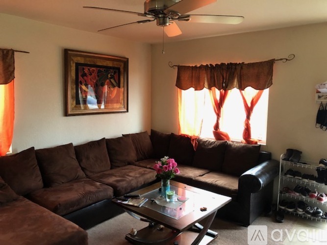 A living room with a brown sofa and a painting on the wall.