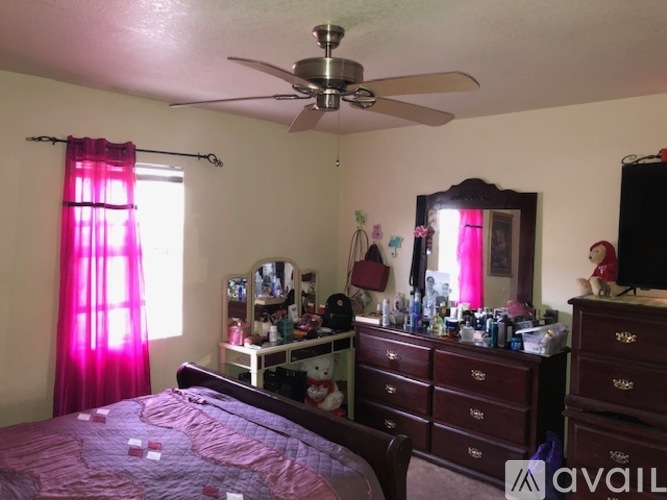 A bedroom with a bed, dresser, mirror, and a ceiling fan.