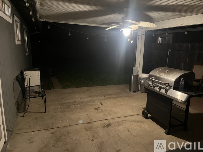 A dark patio with a grill and a fan.