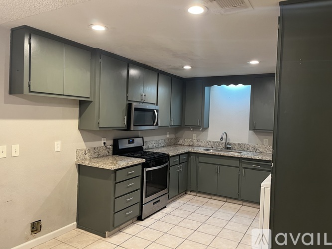 A kitchen with grey cabinets and a granite countertop.