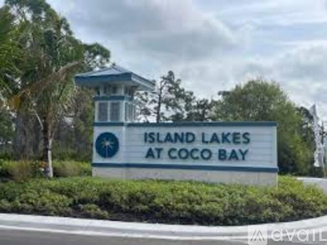 A sign for Island Lakes at Coco Bay is displayed in front of a building.