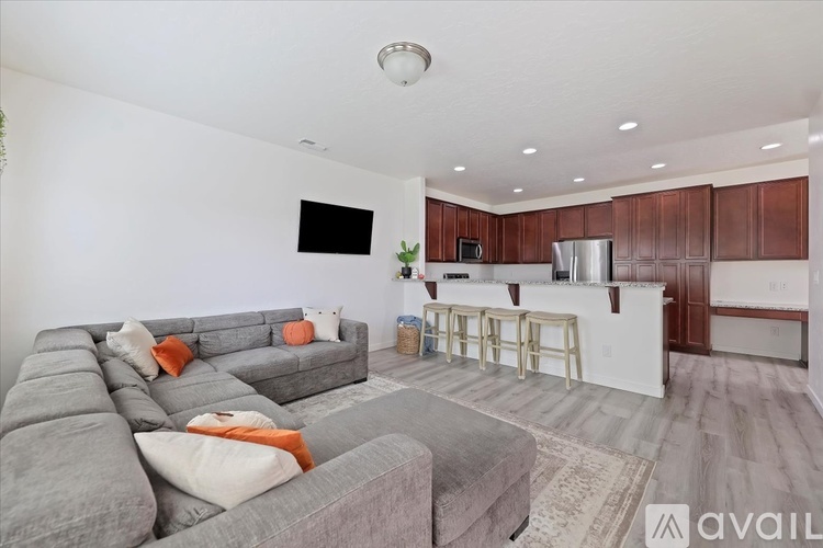 A living room with a grey couch and a bar area in the background.