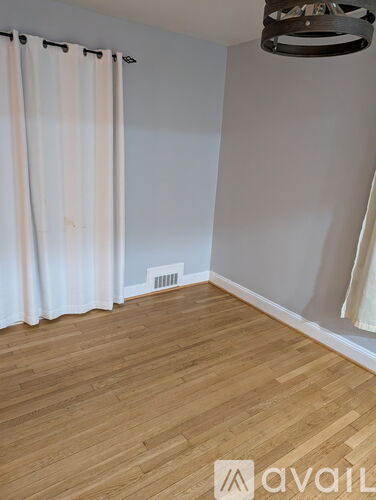 A room with wooden flooring and a white curtain.