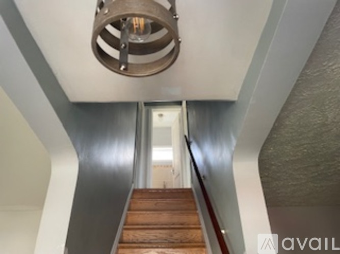A staircase with a wooden handrail and a light fixture above it.