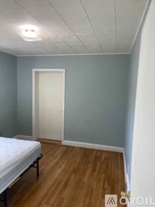 A bedroom with a bed, wooden floor, and a door.