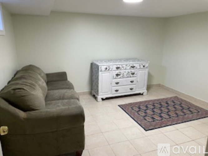 A living room with a brown couch and a white chest of drawers.