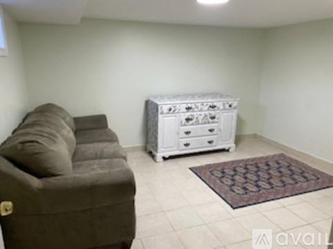 A living room with a brown couch and a white chest of drawers.