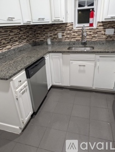 A kitchen with white cabinets and a black dishwasher.