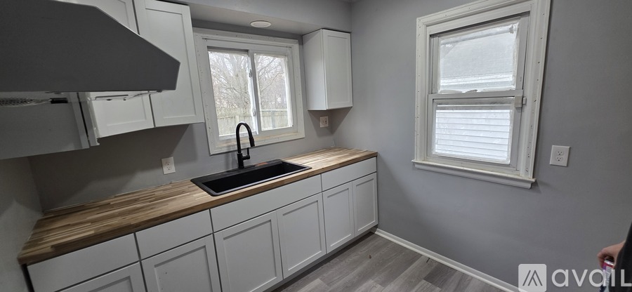 A kitchen with white cabinets and a wooden countertop.