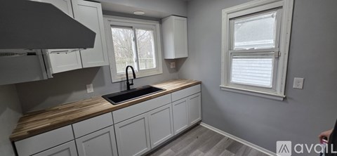 A kitchen with white cabinets and a wooden countertop.