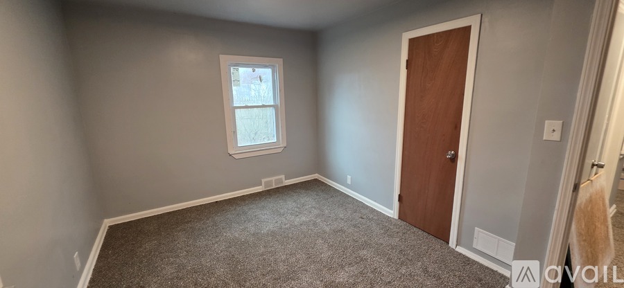 A room with a carpeted floor, a door, and a window.