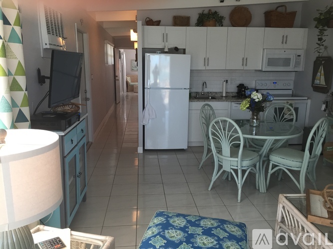 A kitchen with a white refrigerator, a table with chairs, and a patterned rug.