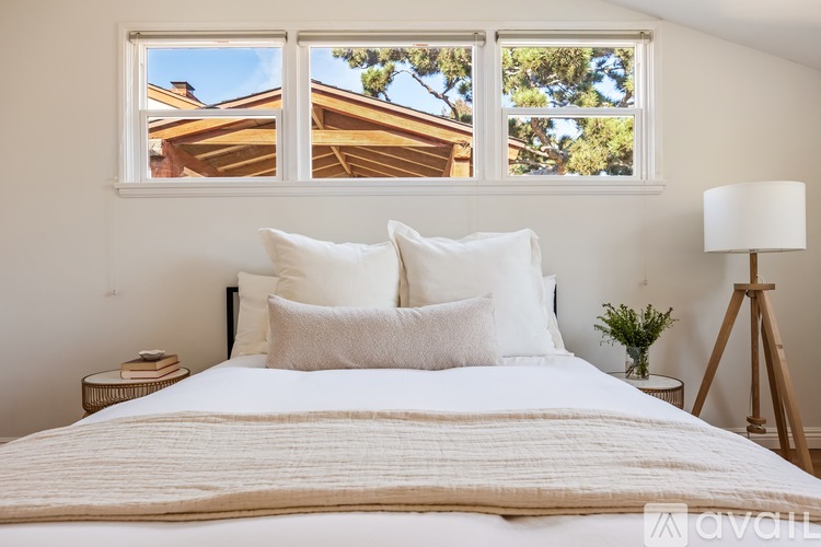 A bedroom with a large bed and a window overlooking a house.