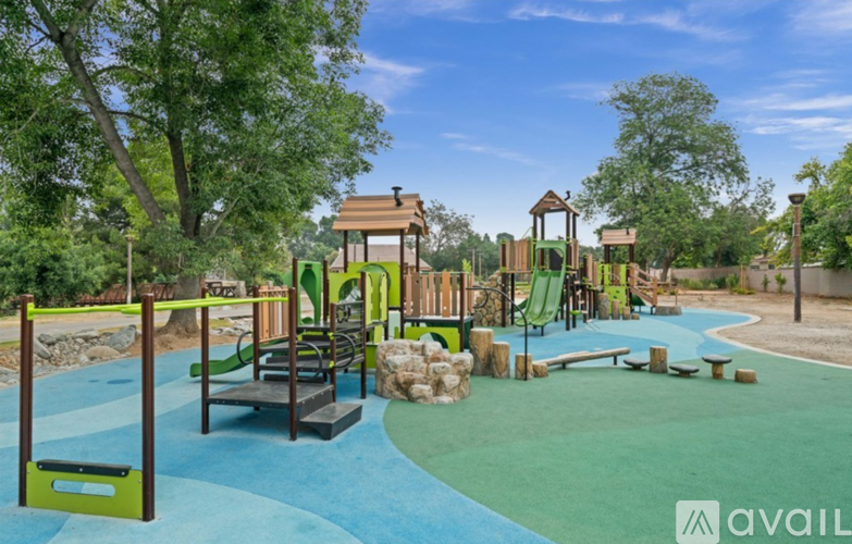 A playground with a green slide, a wooden structure, and a blue surface.