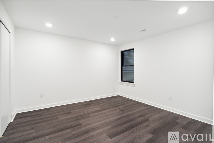 A spacious room with wooden flooring and a window.