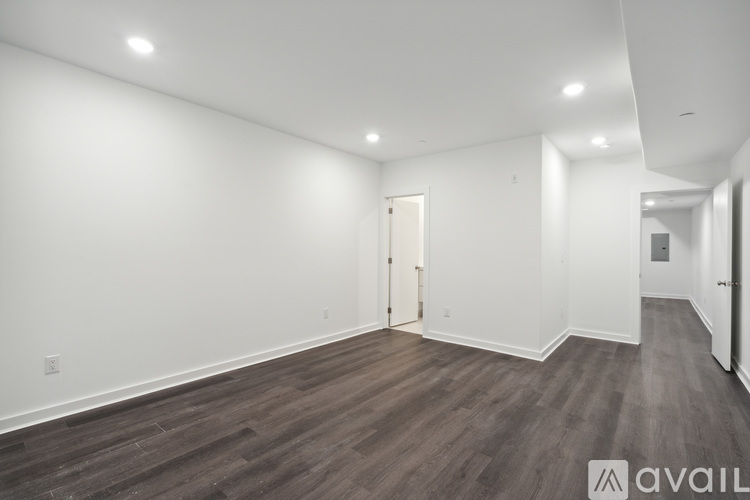 A spacious room with wooden flooring and white walls.