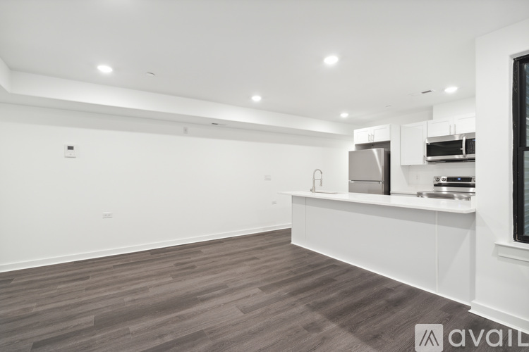 A modern kitchen with white cabinets and a wooden floor.