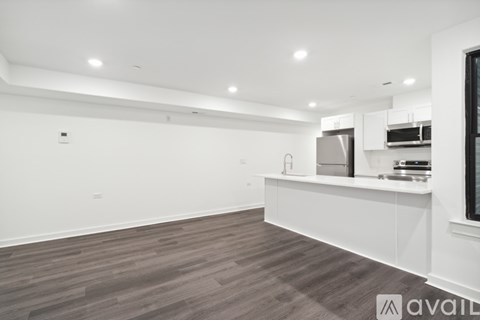 A modern kitchen with white cabinets and a wooden floor.
