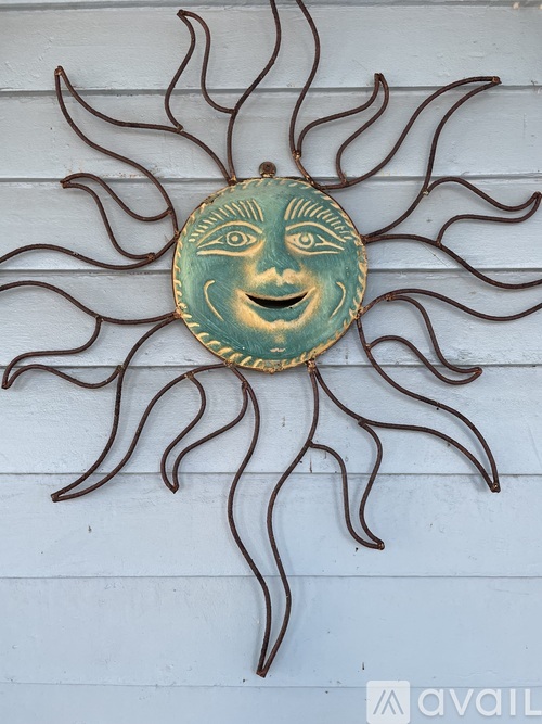 A sun with a face in the middle is hanging on a wall.