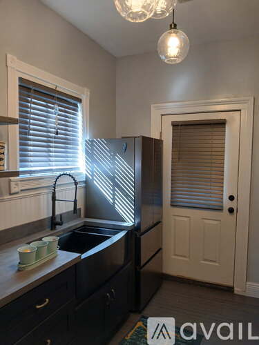 A kitchen with black cabinets and a sink under a window.