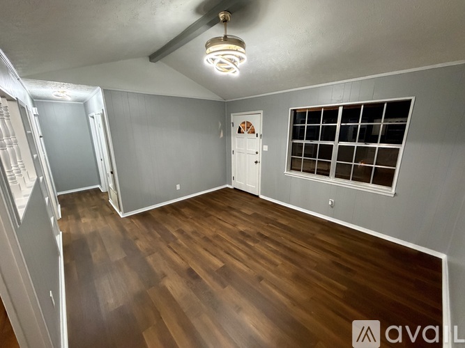 A room with wooden flooring and a window with bars on it.