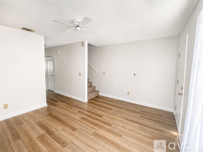 A hallway with a white door and a kitchen area with a white refrigerator.