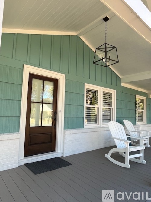 A porch with a rocking chair and a door.