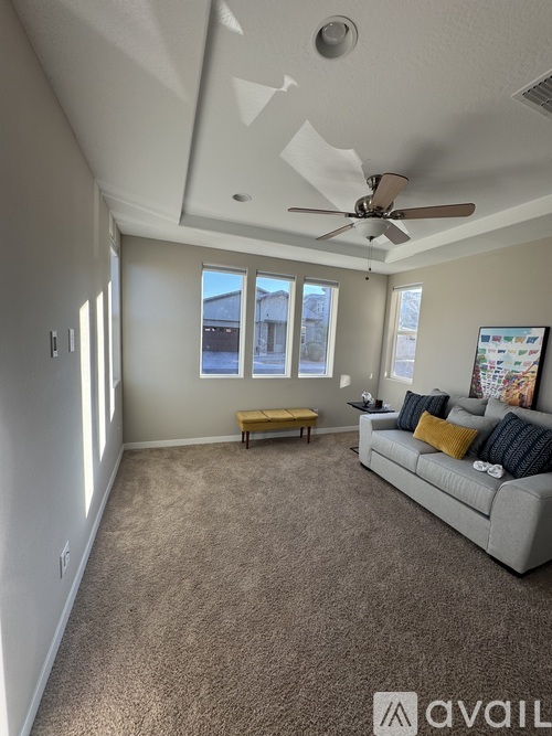 A living room with a grey couch and a fan on the ceiling.