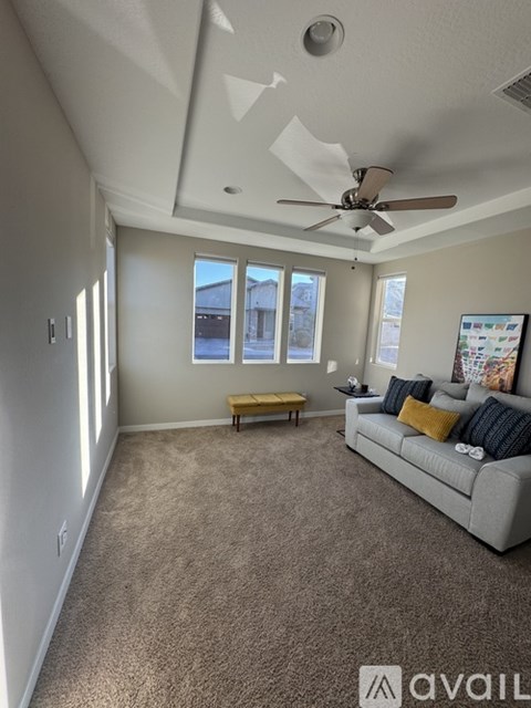 A living room with a grey couch and a fan on the ceiling.