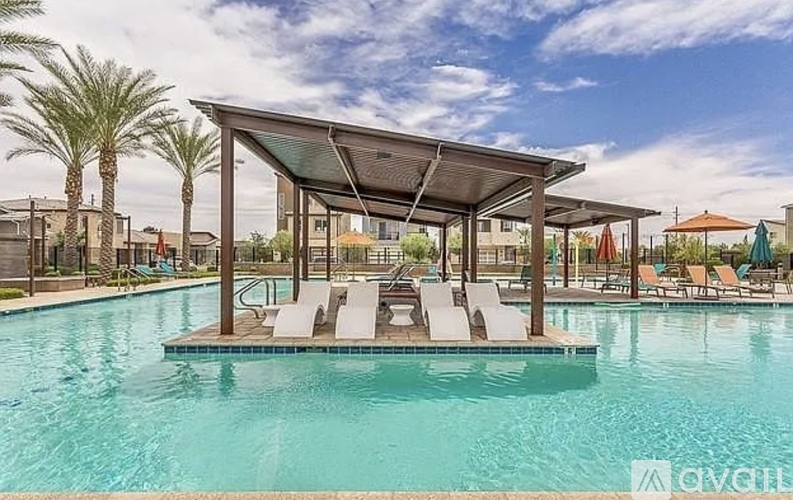 A swimming pool with a pavilion and lounge chairs.