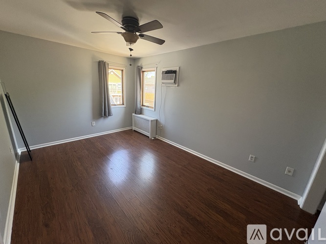 A room with a ceiling fan and wooden flooring.