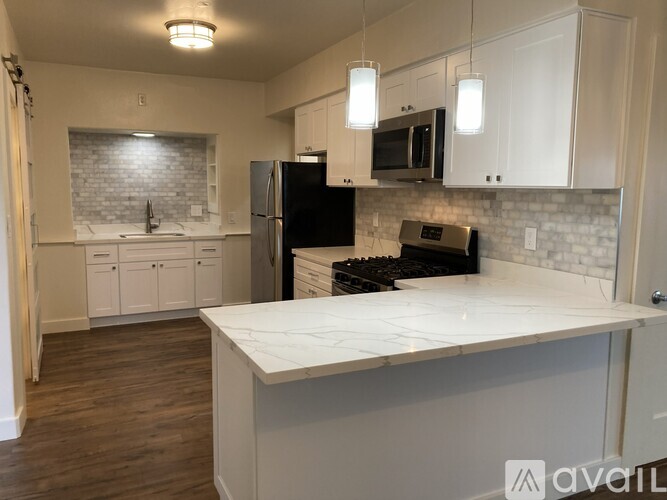 A kitchen with a black refrigerator and white cabinets.