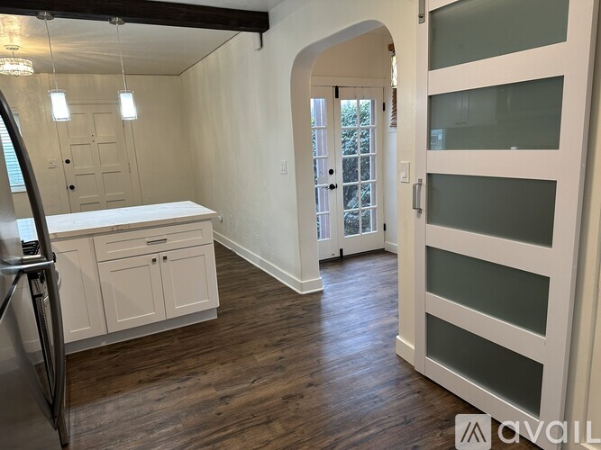 A kitchen with white cabinets and a white countertop with a refrigerator to the left.