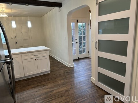 A kitchen with white cabinets and a white countertop with a refrigerator to the left.