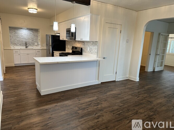 A kitchen with white cabinets and a black refrigerator.