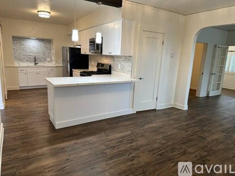 A kitchen with white cabinets and a black refrigerator.