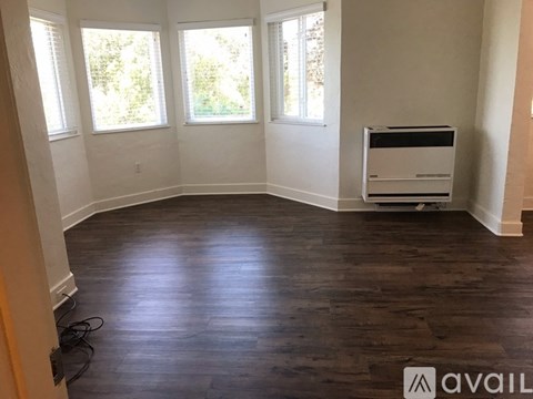 A room with wooden floors and a window with a view of trees.