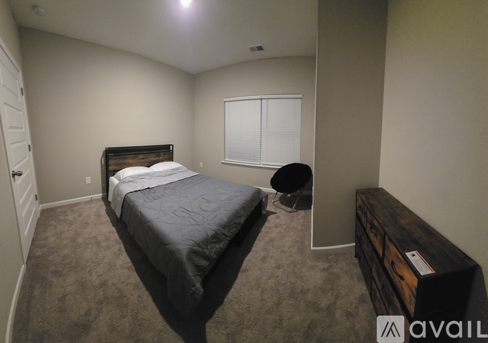 A bedroom with a bed, dresser, and window.