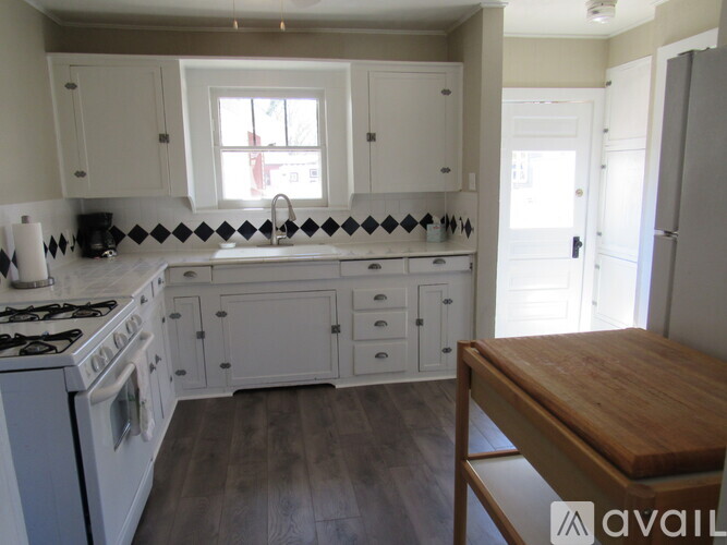 A kitchen with white cabinets and a wooden table.