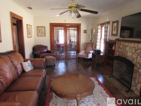 A living room with a brown leather couch and a fireplace.