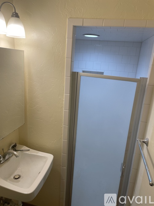 A bathroom with a sink, mirror, and shower.